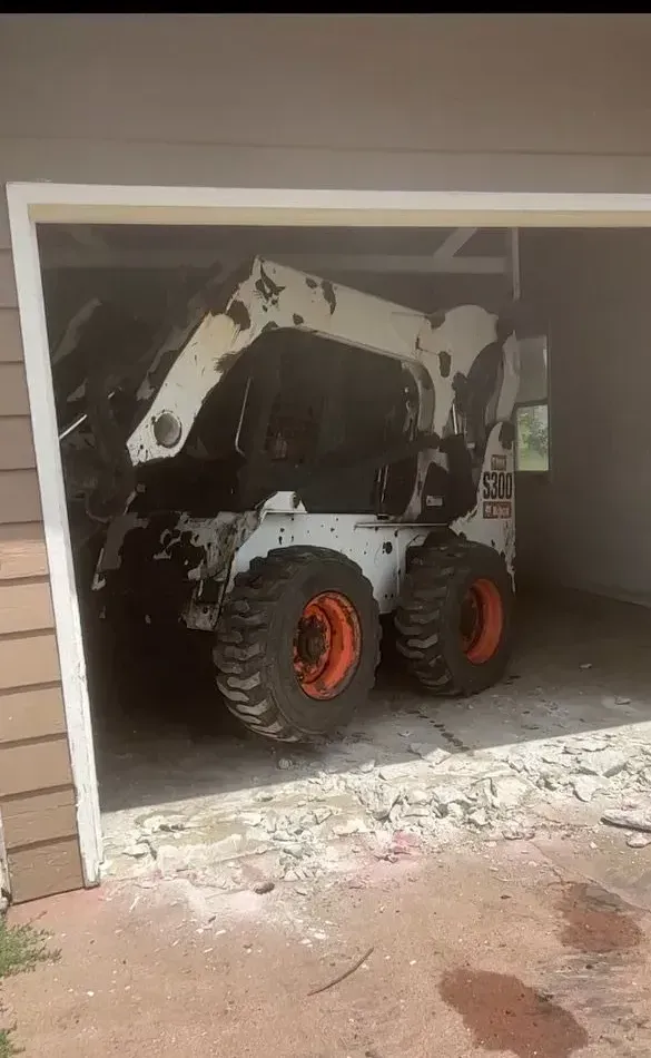 A bobcat is parked in a garage door.
