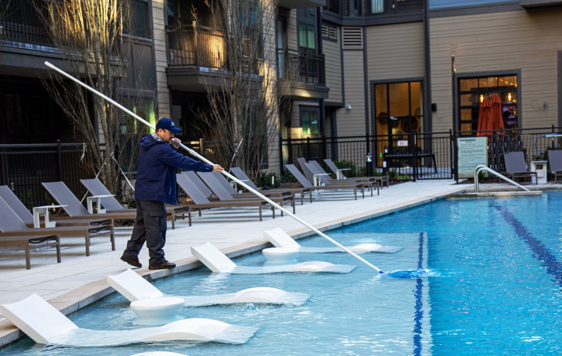 A man is cleaning a swimming pool with a mop