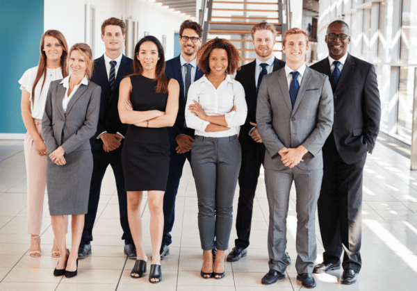 A group of business people are posing for a picture in a hallway.