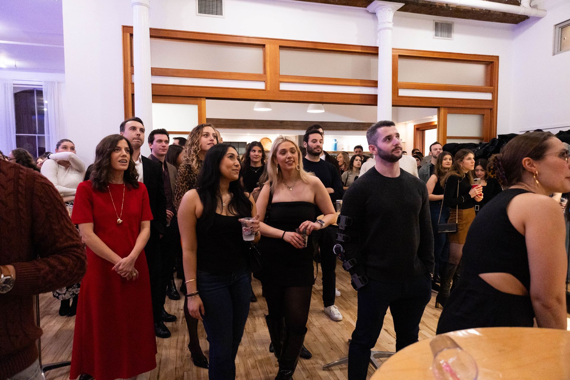 A group of people are standing in a room looking up at something.