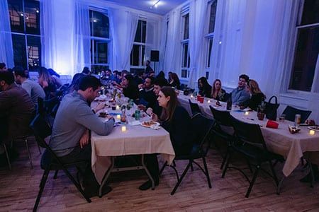 A group of people are sitting at long tables in a room.