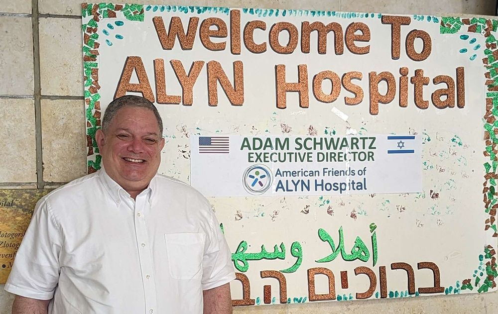 A man stands in front of a sign that says welcome to alyn hospital