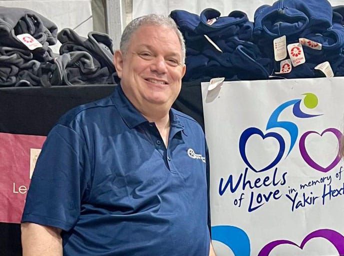 A man is standing in front of a sign that says wheels of love