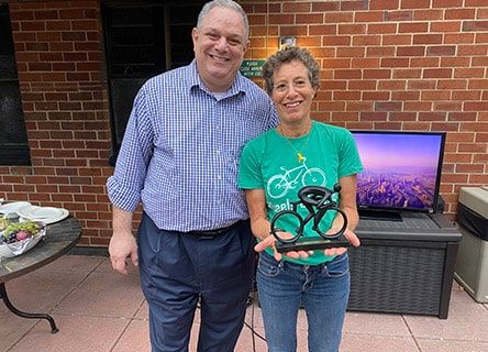 A man and a woman are standing next to each other holding a trophy.