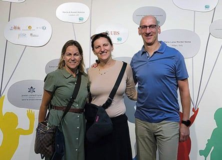 Three people are posing for a picture in front of a wall with speech bubbles.