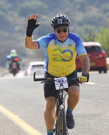 A man wearing a helmet and sunglasses is riding a bike down a road.