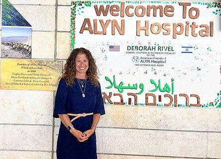 A woman is standing in front of a sign that says welcome to alyn hospital