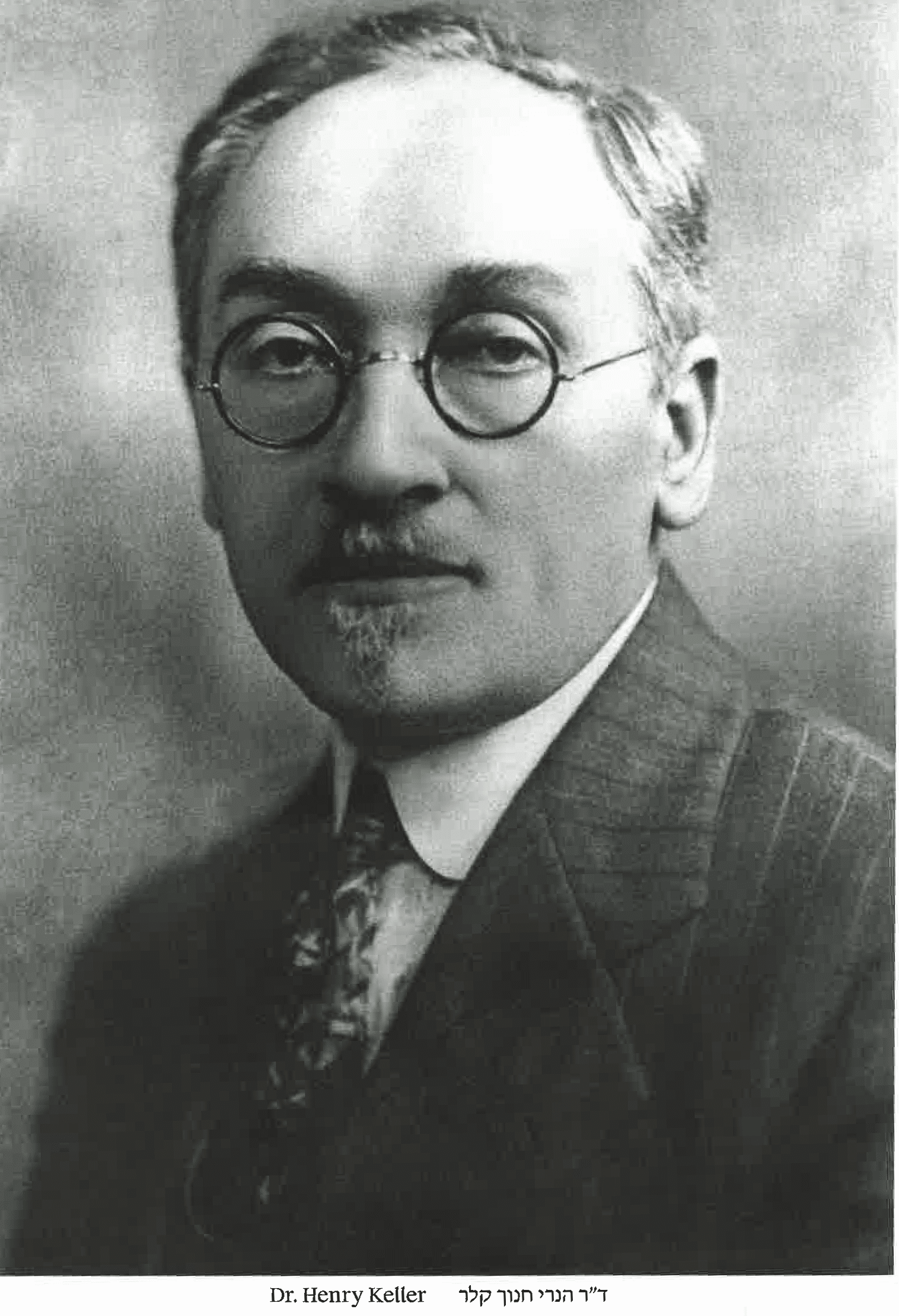 A black and white photo of a man wearing glasses and a suit