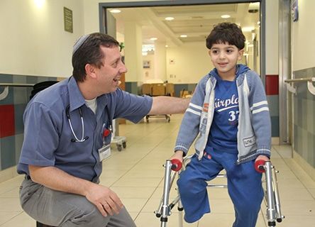 A young boy with crutches is being helped by a doctor