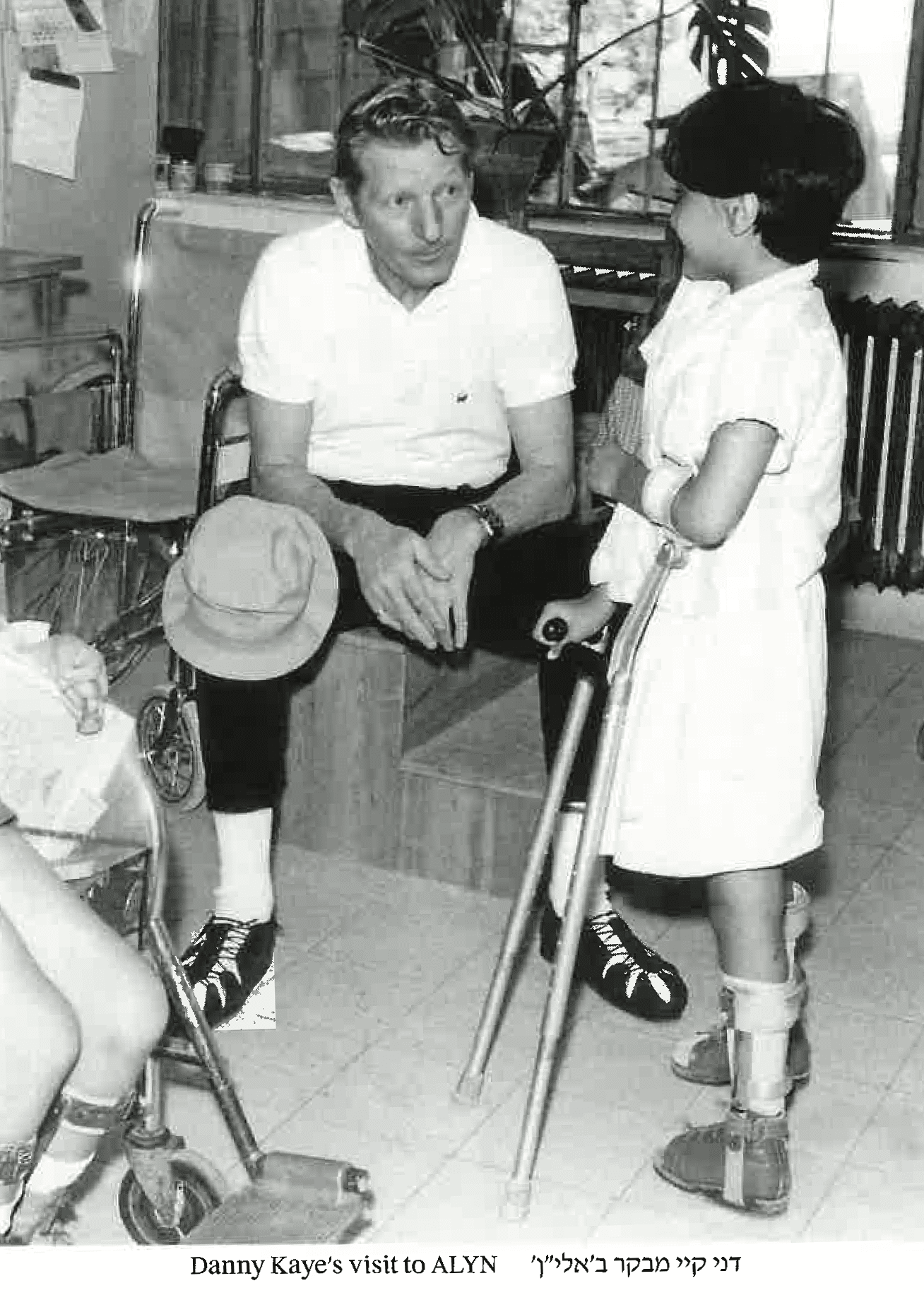 A black and white photo of a man sitting next to a child with crutches