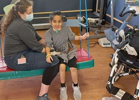 A woman is sitting next to a little girl on a swing.