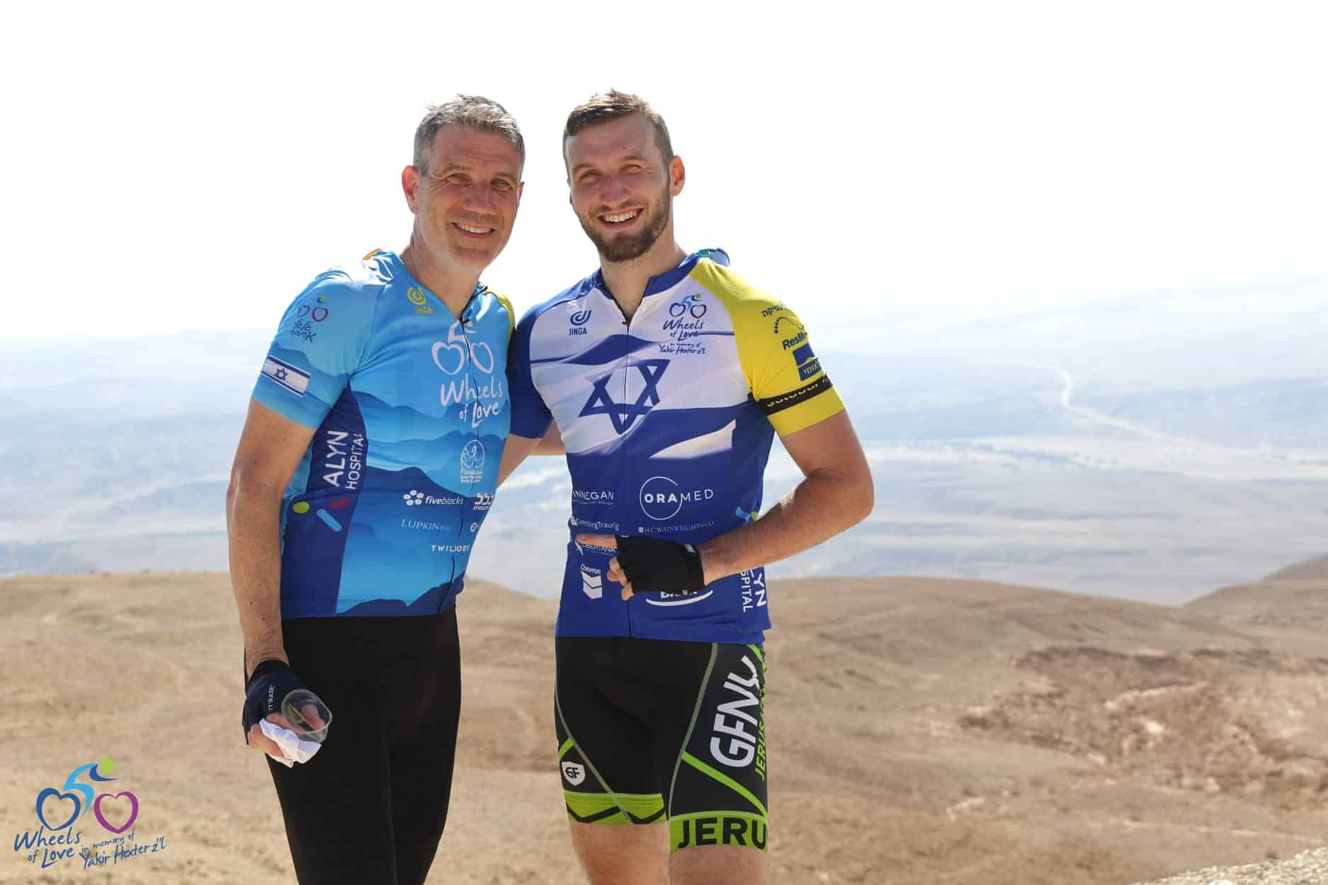 Two men are posing for a picture on top of a mountain.