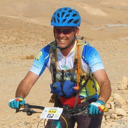 A man wearing a helmet and sunglasses is riding a bike