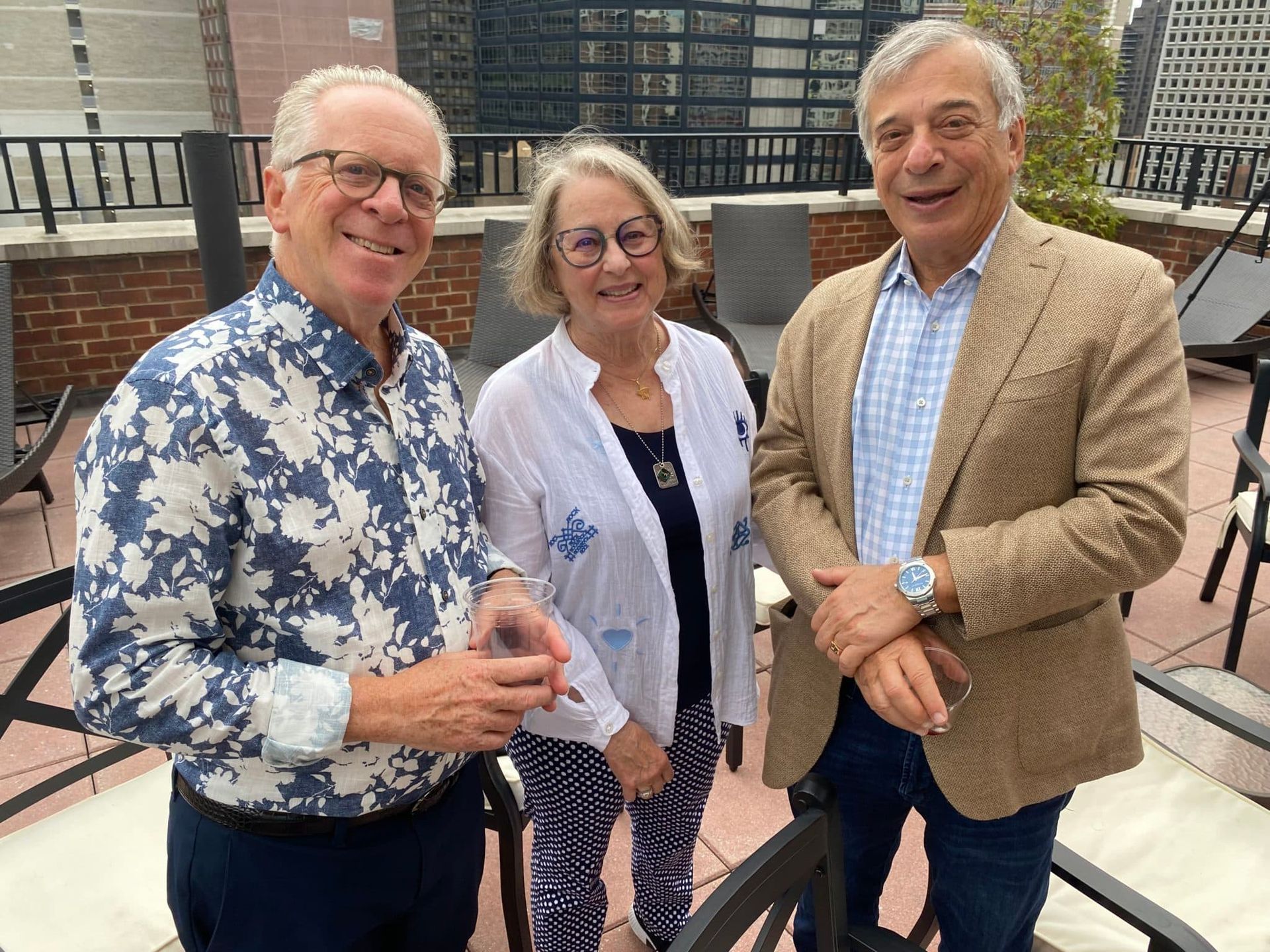 Three people are standing next to each other on a patio.