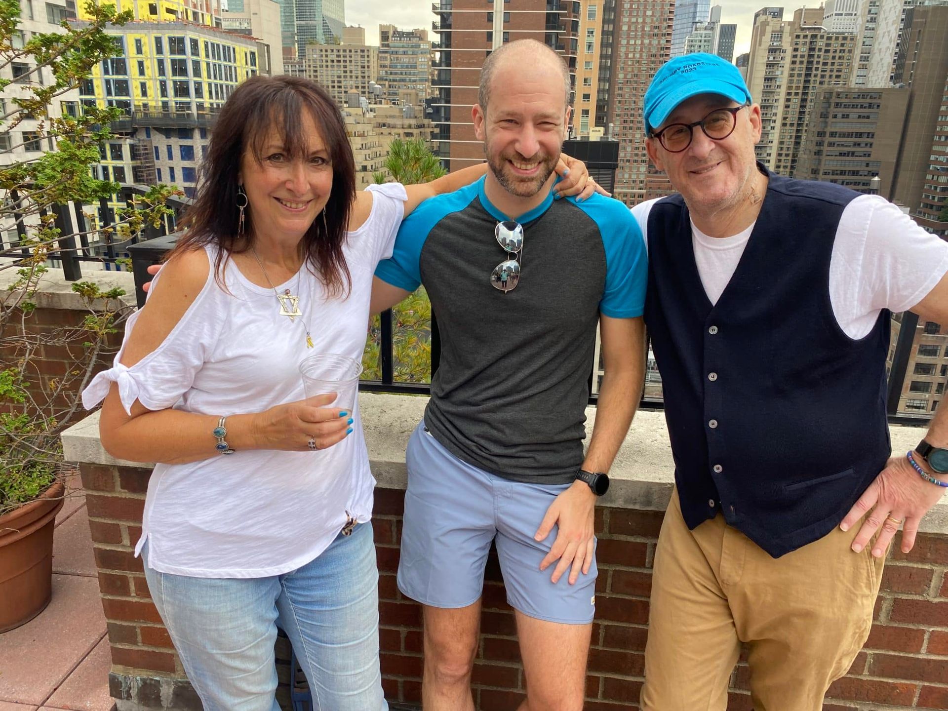 Three people are posing for a picture on a balcony.