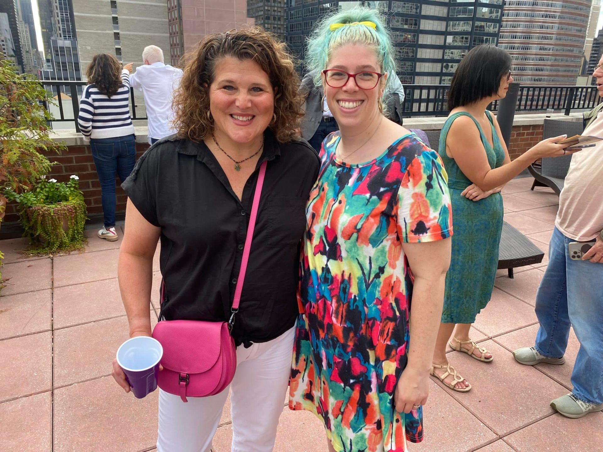 Two women are posing for a picture on a rooftop.