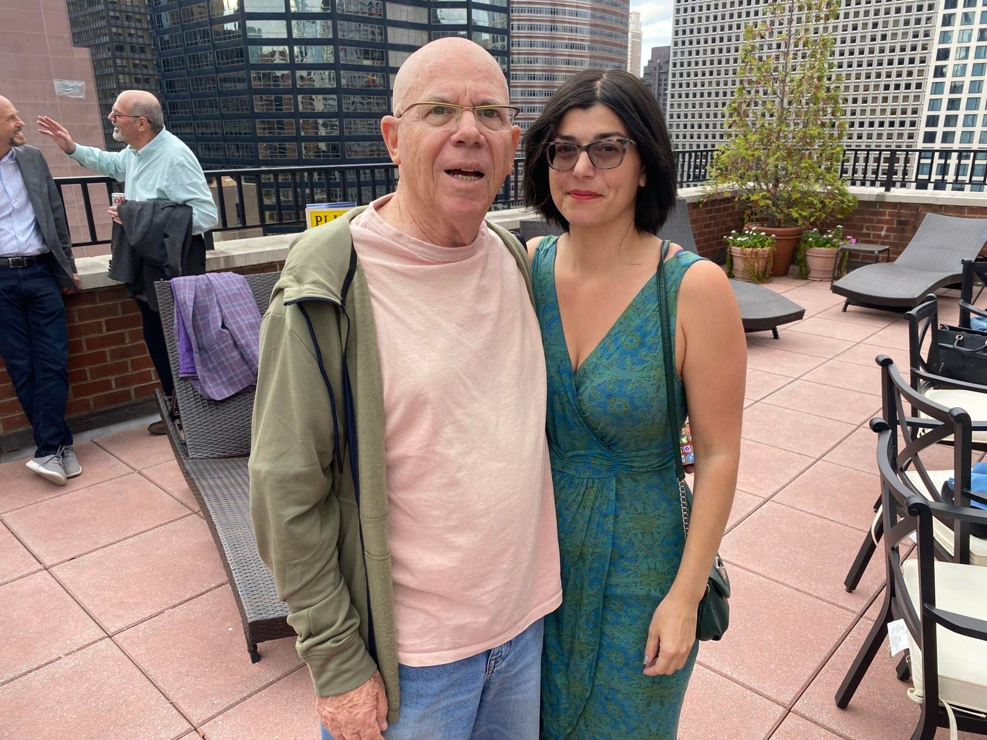 A man and a woman are posing for a picture on a rooftop.