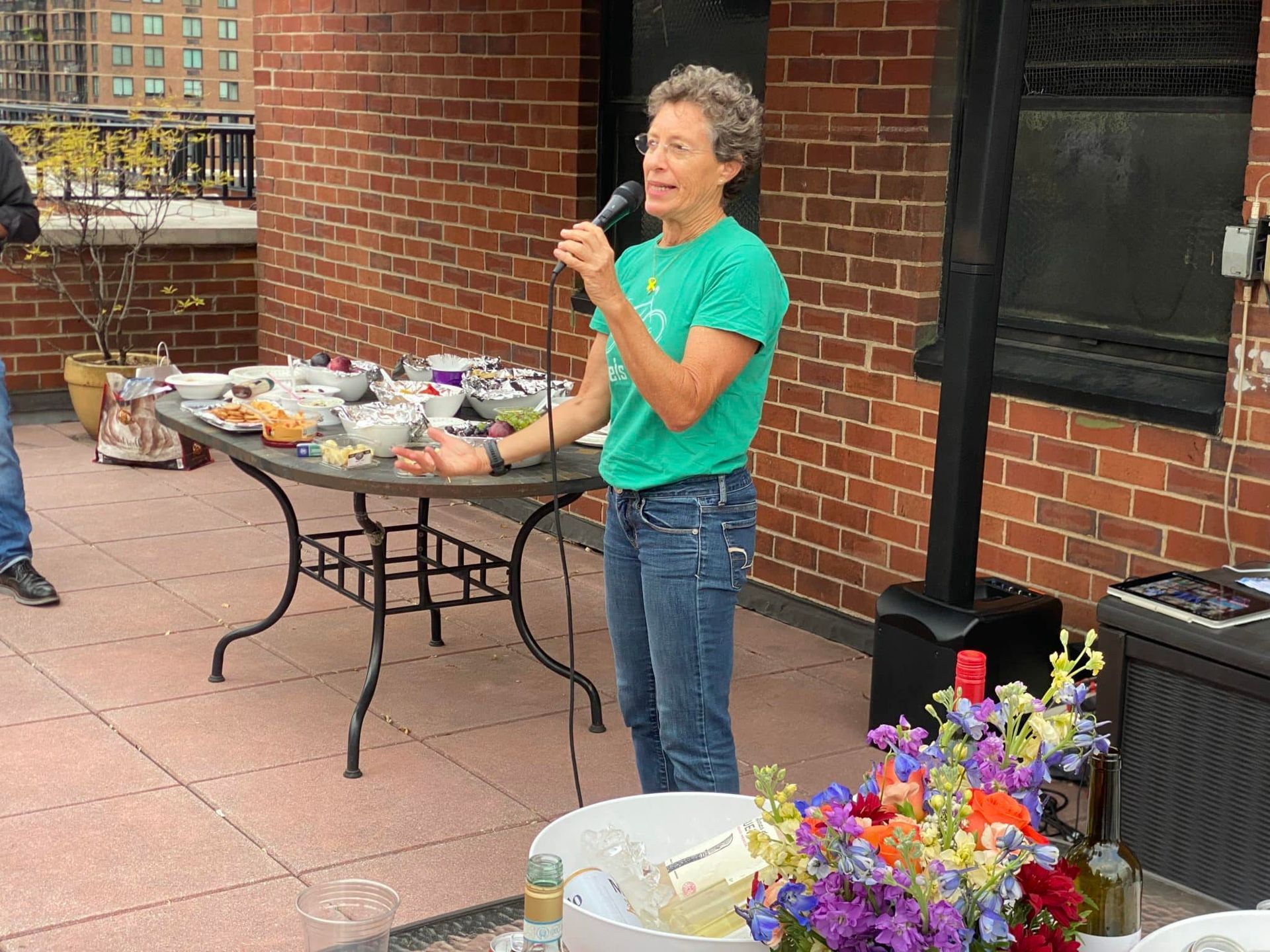 A woman is standing in front of a table holding a microphone.