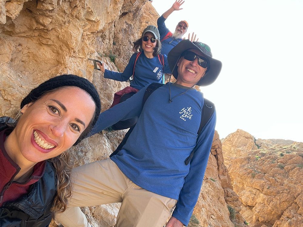 A group of people are standing on top of a rocky cliff.
