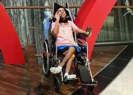 A man in a wheelchair is talking on a cell phone.