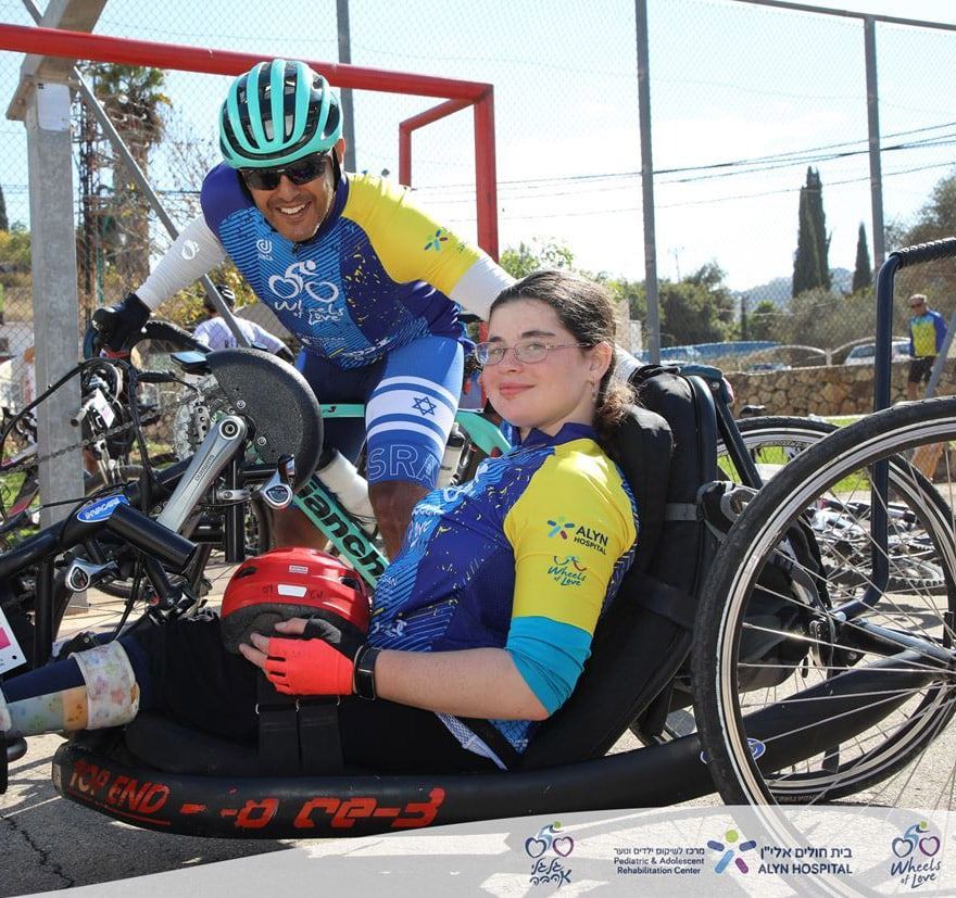 A man is riding a bike next to a woman in a wheelchair