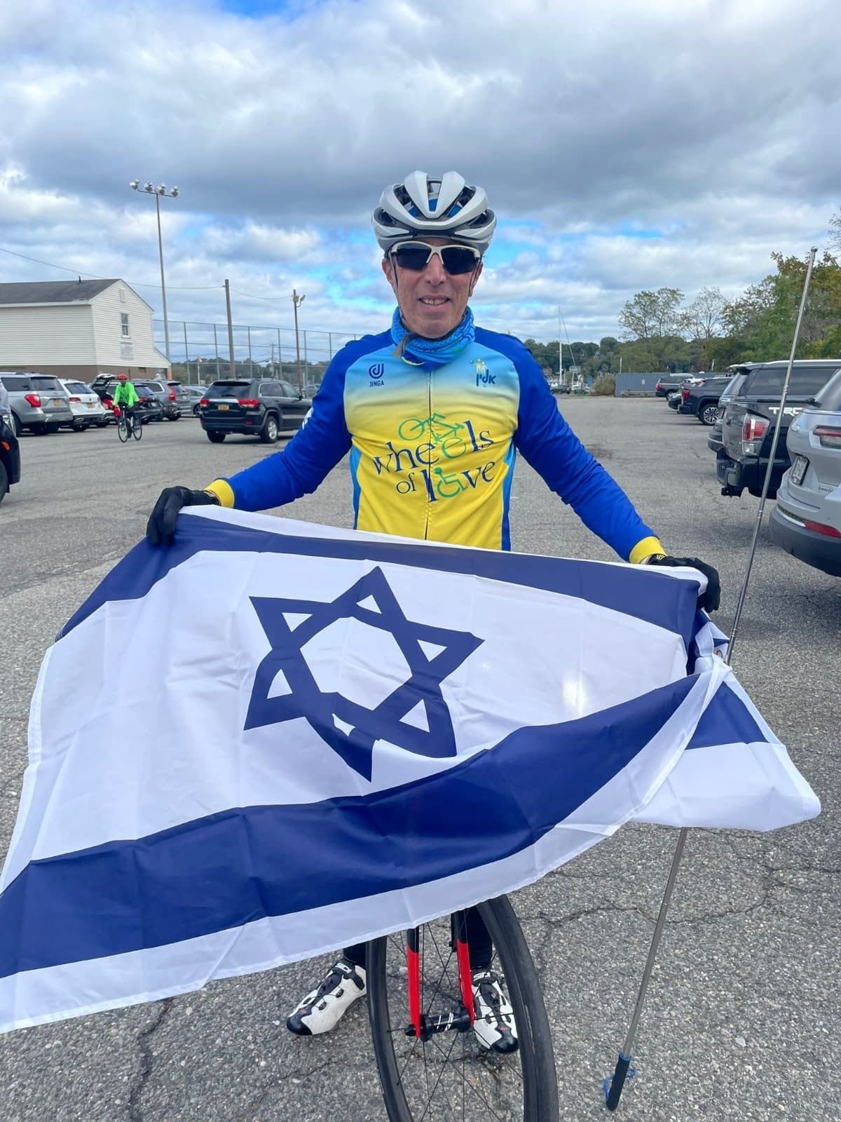 A man is holding a flag with a star on it in a parking lot.
