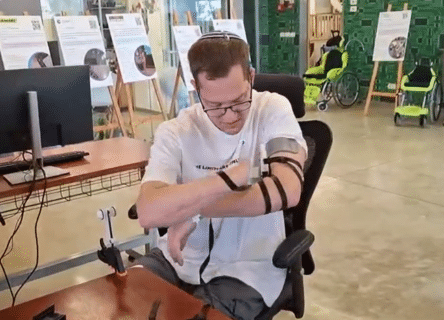 A man with a prosthetic arm is sitting at a desk.