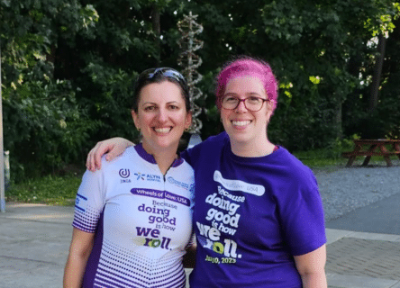 Two women are posing for a picture and one has pink hair.