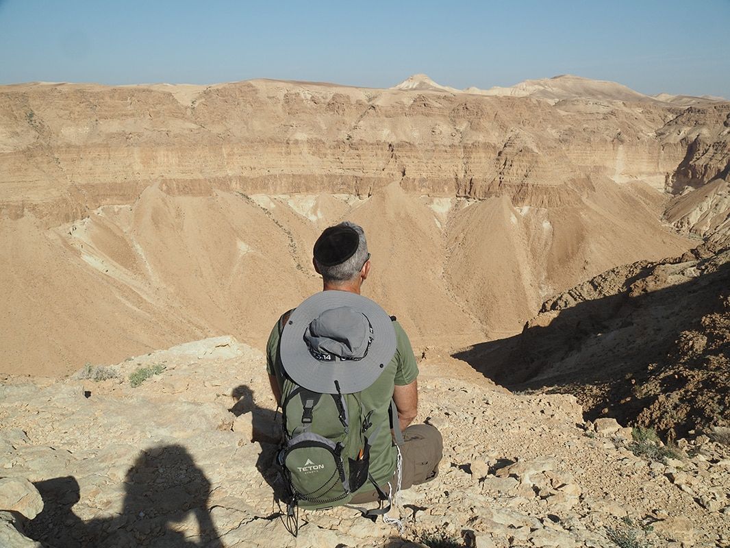 A man with a backpack is sitting on top of a rocky hill