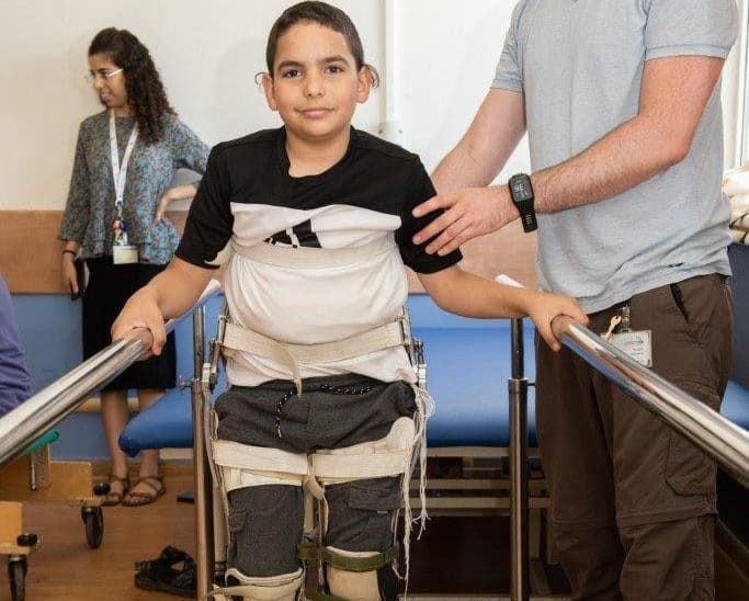 A young boy in a wheelchair is being helped by a man.