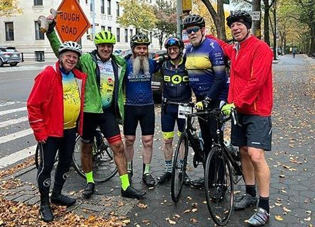 A group of cyclists are posing for a picture on the side of the road.