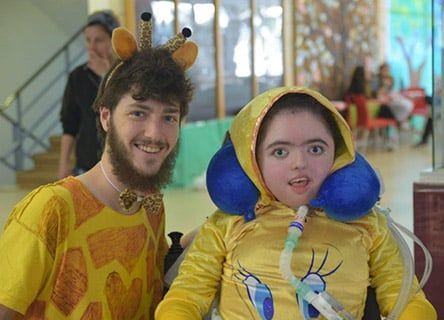 A man and a child in a giraffe costume are posing for a picture.