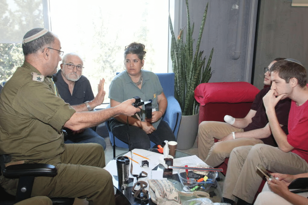 A man in a military uniform is talking to a group of people