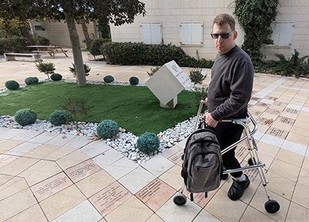 A man with a backpack is walking with a walker