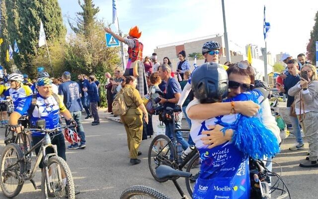 A group of people are riding bicycles down a street and hugging each other.
