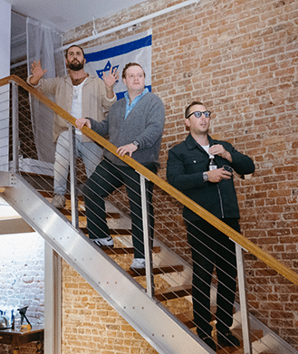 Three men are standing on a set of stairs in front of a brick wall