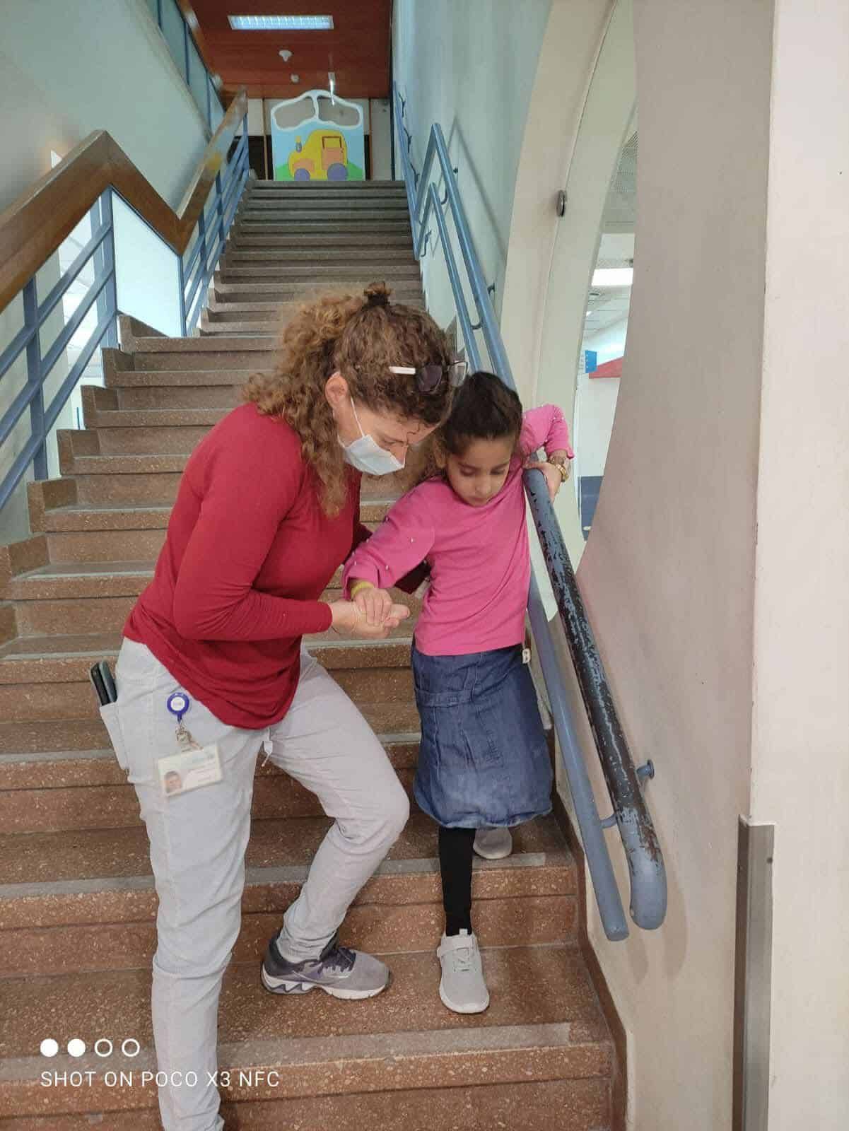 A woman is helping a little girl up the stairs.