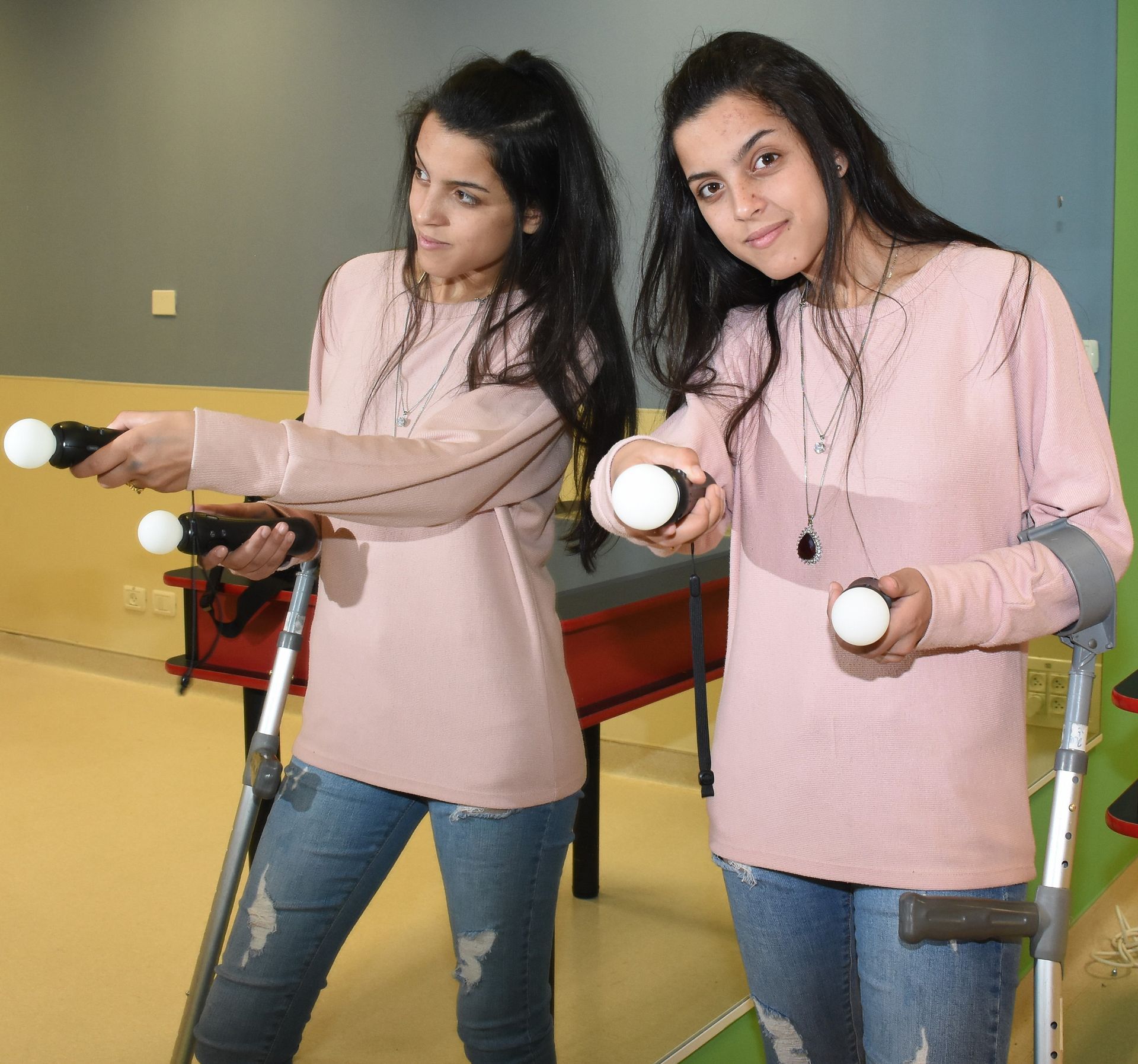 Two girls are standing next to each other holding remotes