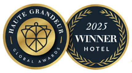 Two circular navy blue and gold Haute Grandeur Global Awards 2025 winner badges for hotels.