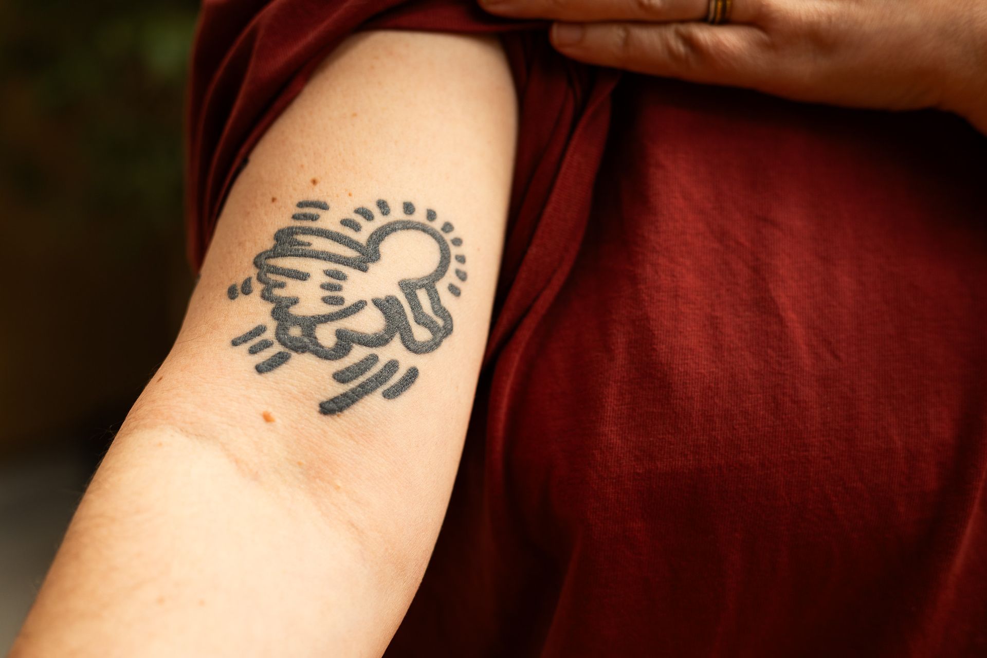 Close-up van een onderarm met een zwarte tattoo van een engel.