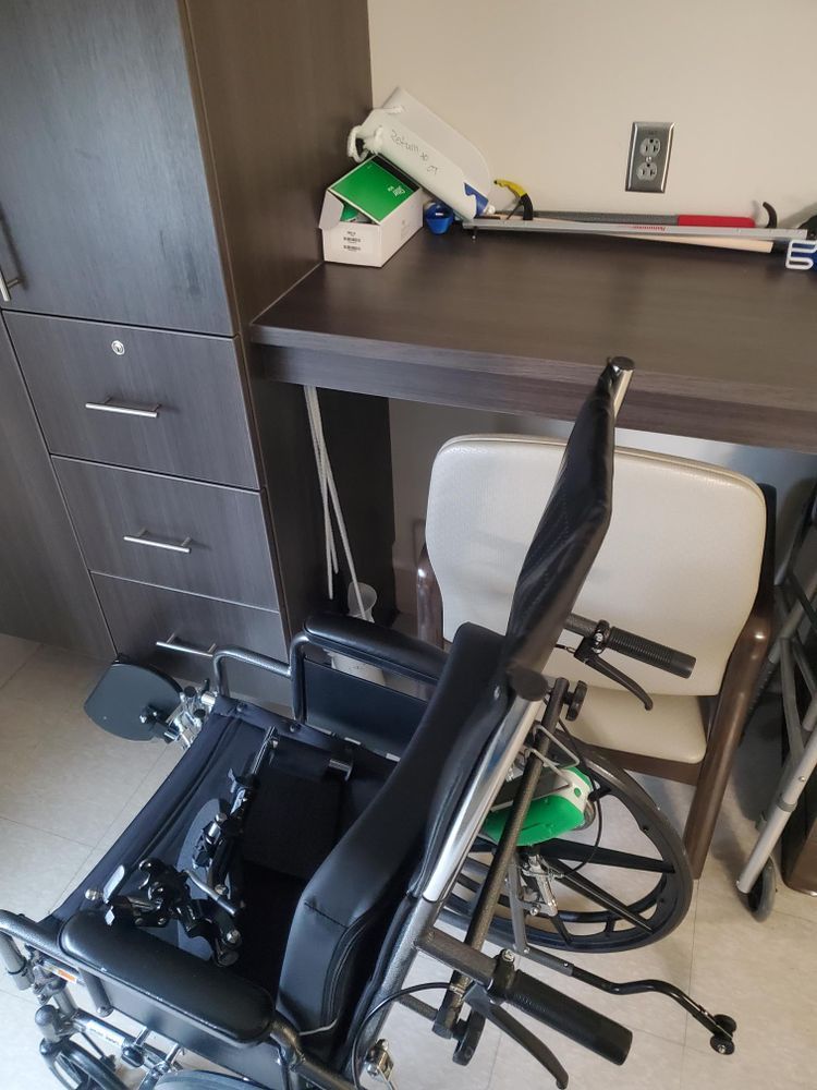 A wheelchair is sitting under a desk in a room