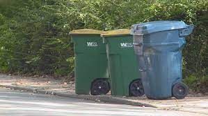 Two trash cans are parked on the side of the road