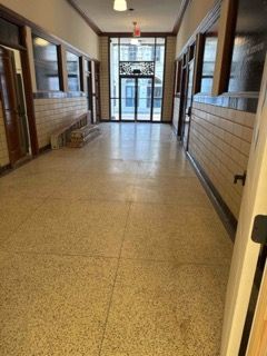 Hallway with beige tile floor, brick wall, and glass doors at the end.