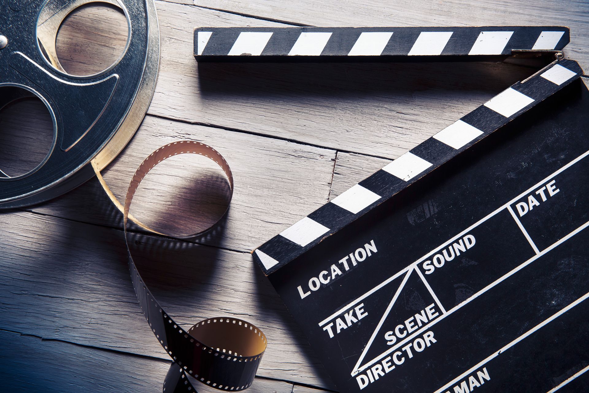 A clapper board and a roll of film on a wooden table