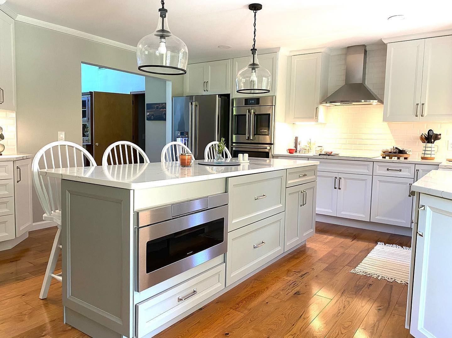 A kitchen with white cabinets , stainless steel appliances and a large island.