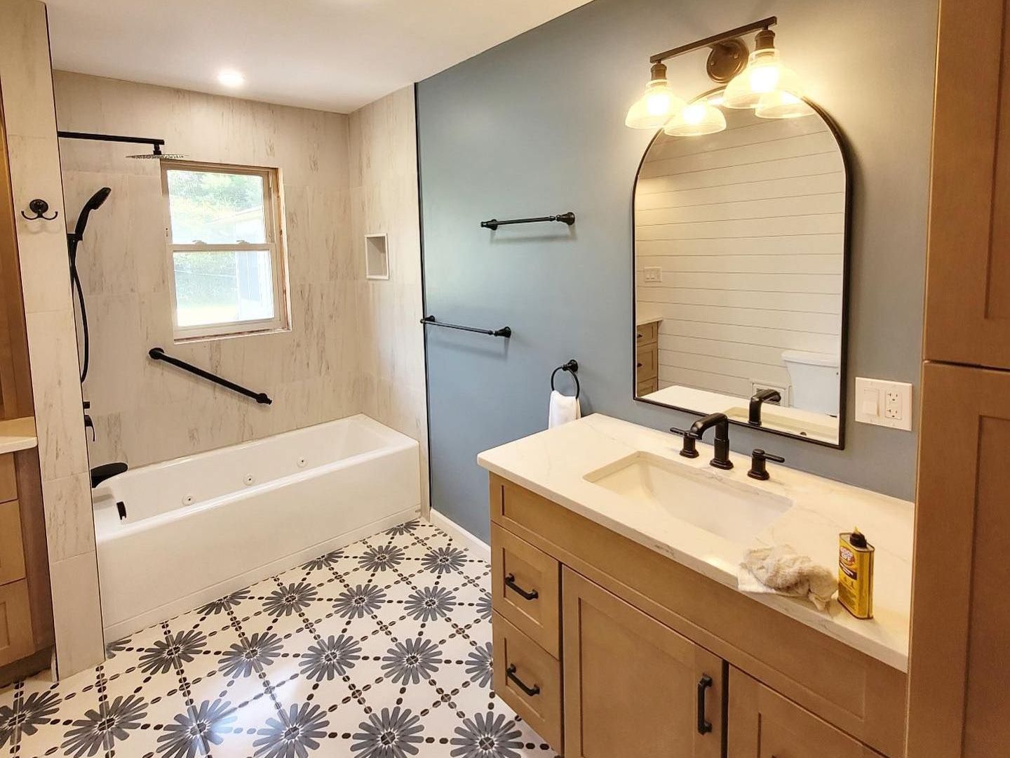A bathroom with a sink , tub and mirror.