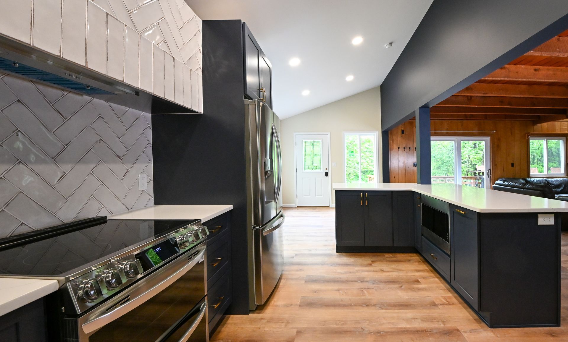 A kitchen with green cabinets , a coffee maker , and a ladder. Modern kitchen with blue cabinets, stainless steel appliances, and white countertops.