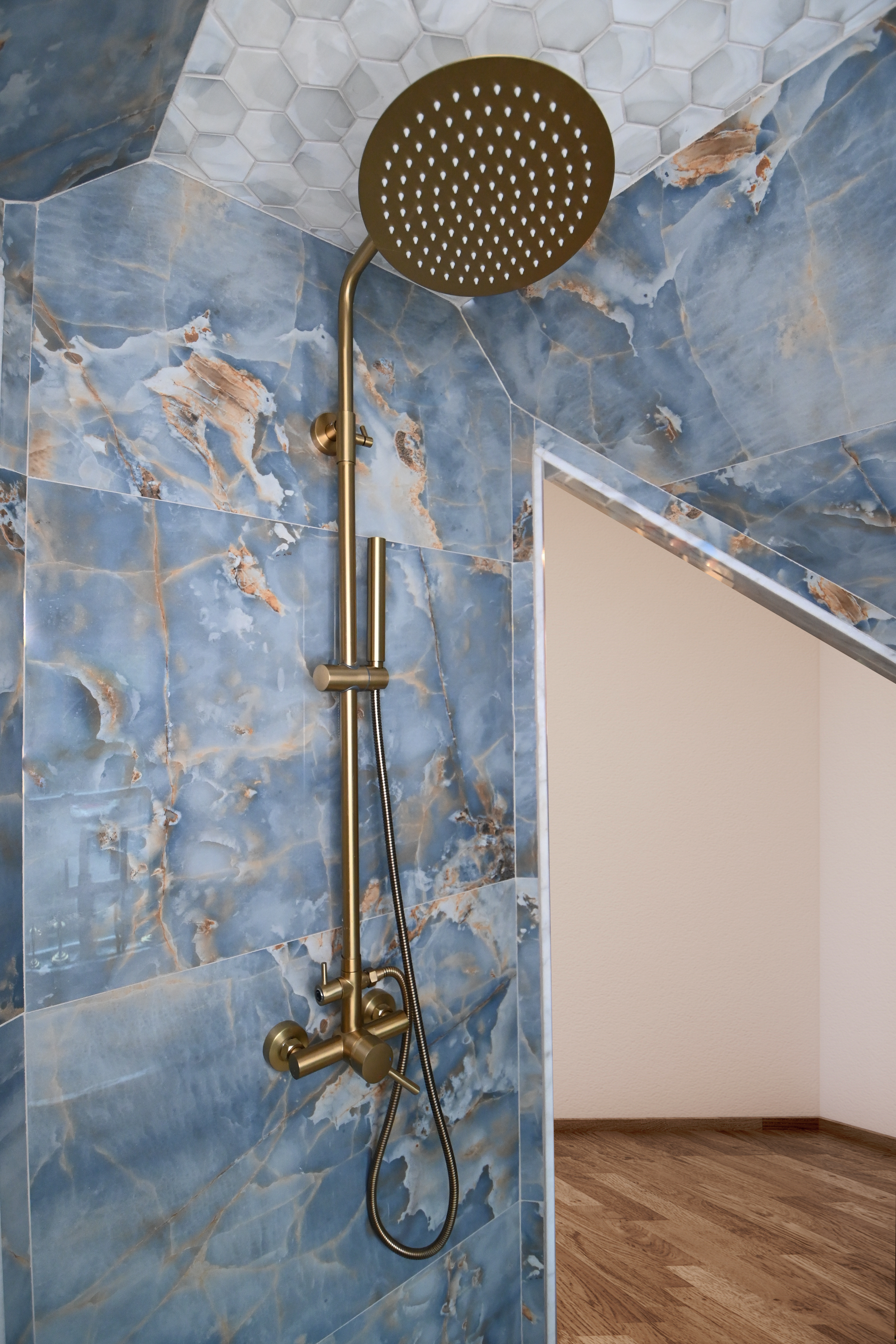 Gold shower head against blue marble tiled wall.