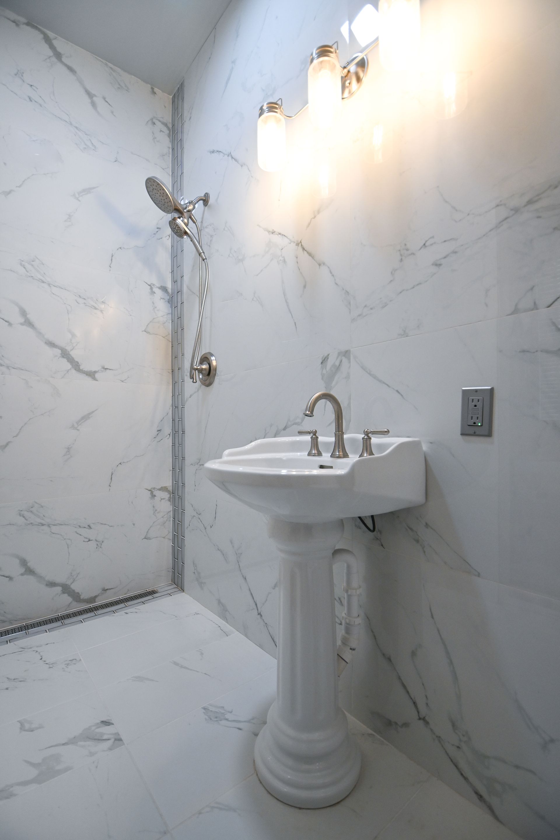 A bathroom with a pedestal sink and a shower.
