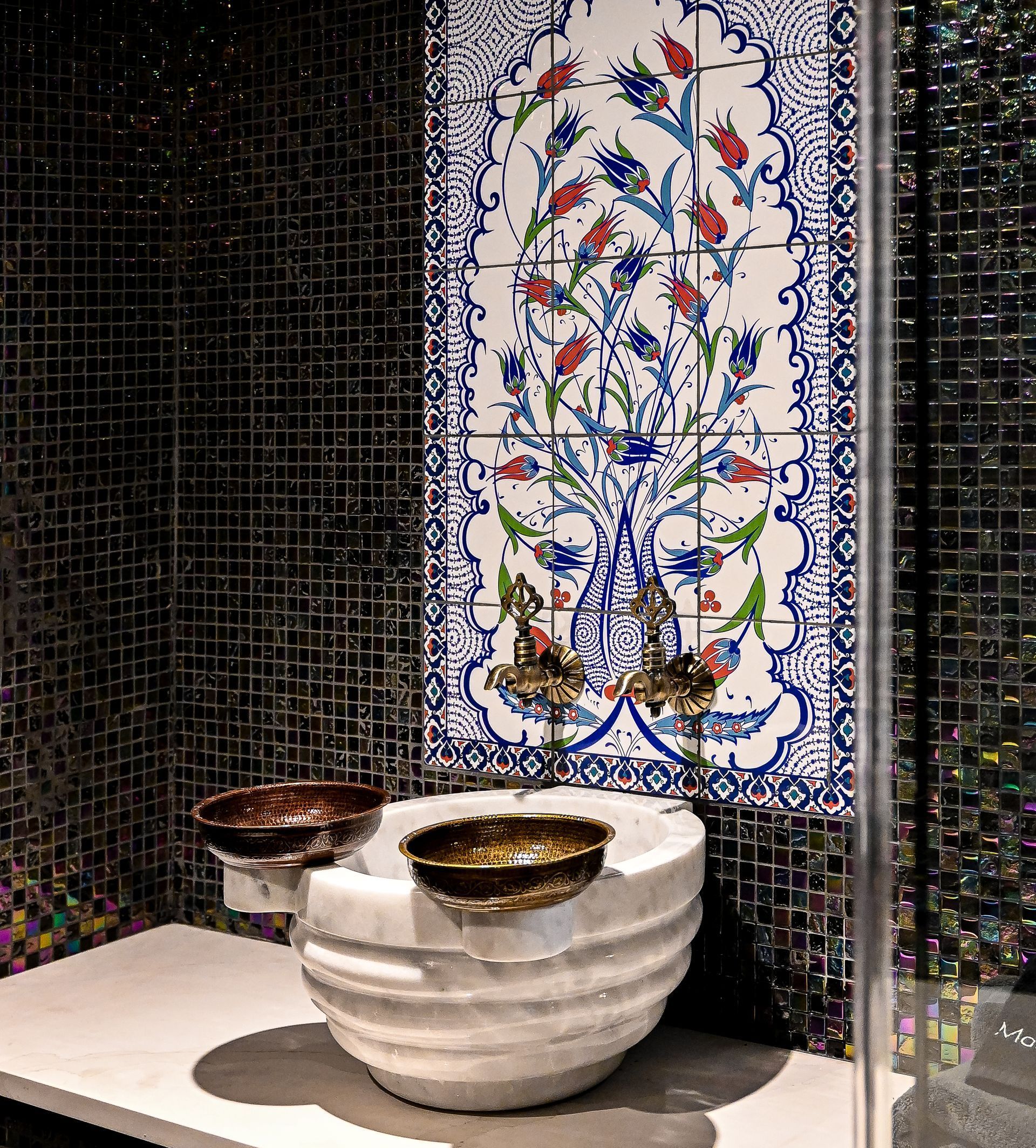 A bathroom with a floral tile on the wall and a sink